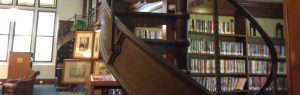 Twisting staircase in foreground, shelves of books in background