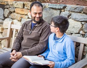 A picture of a father and his son sitting on a bench.