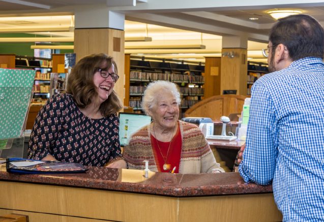 A picture of three people at the front desk.