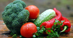 Pile of vegetables including broccoli, tomatoes, a cucumber, and red peppers