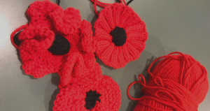 Three Red Crocheted Poppies with the red yarn next to them