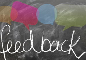 the word feedback on a chalkboard with colored speech bubbles above it