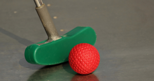 green putter next to an orange mini golf ball