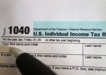 1040 Tax Form with a pen about to write on it