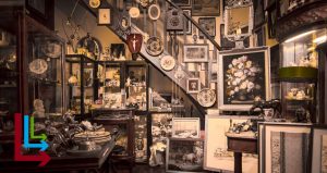 Room full of antiques like photos, doohickeys, statues, and other old things. With the overlay of the Live Long and Learn logo in the left hand corner