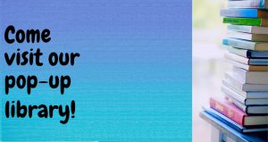 The words Come visit our pop-up library on a blue background next to a pile of multicolored books