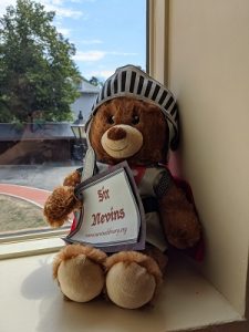 Brown teddy bear dressed as a knight holding a sword and a sign that says Sir Nevins