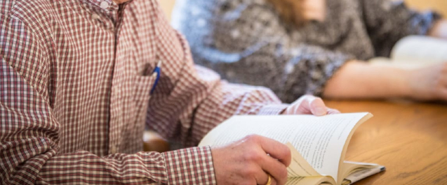 upper body and arms of a man reading a book