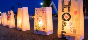 Luminaria bags with messages and pictures drawn on them and candles lighting them from the inside out