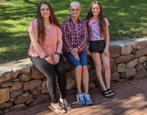 Two young women and one older woman sitting on a stone wall