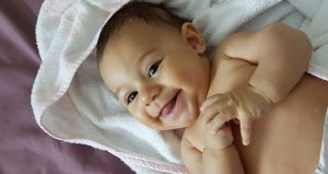 Smiling baby laying on a plush white towel