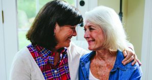 Two older ladies, one brunette one white haired, hugging