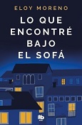 Dark Blue covered book with three partially shadowed houses some with lights on in their windows. The name Eloy Moreno above and the title Lo Que Encontre Bajo El Sofa