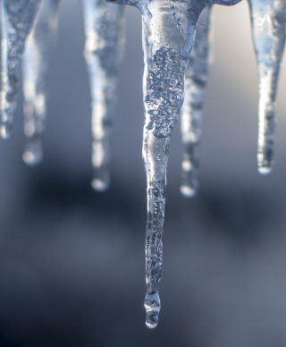 Icicles hanging down in the foreground and a blurry grey background