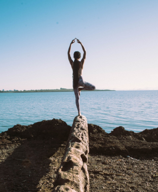 Woman standing on the edge of a rock in a yoga pose