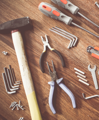 Hammer, screwdrivers, pliers, and other tools on a wooden tabletop