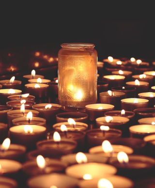 Many small candles on a flat surface with a candle in a mason jar in the middle