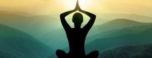 Shadow of a woman in a yoga pose with a green and yellow sunset in the background