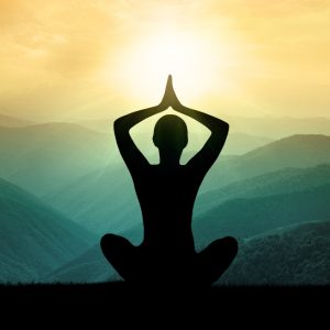 Shadow of a woman in a yoga pose with a green and yellow sunset in the background