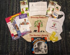 Growing readers bag, growing readers bib, yellow squishy duck, and paper all on the floor