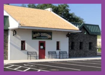 Irish Cottage building, partially made of brick, partially of white stucco with empty parking space in front of it