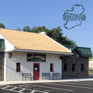 Irish Cottage building, partially made of brick, partially of white stucco with empty parking space in front of it