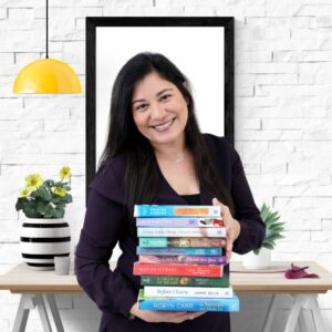 Light skinned woman with black hair smiling with a pile of books in her hands