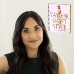 Olive skinned brunette woman in a dark sleeveless shirt standing next to the book Taylor Swift Style