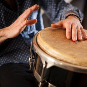Two light skinned hands hitting a drum