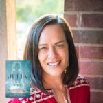 Light skinned brunette female smiling and wearing a red shirt with the inset blue cover of "Julia" next to her