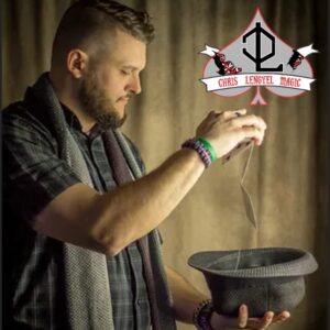 Light skinned man with a beard holding a hat in one hand and dropping playing cards into it from the other