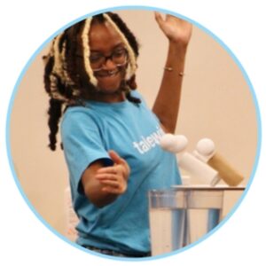 Dark skinned young woman wearing glasses and a light blue tshirt with eggs falling next to her