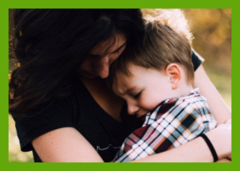 A dark haired light skinned woman holds a brown haired light skinned boy in a hug in her arms