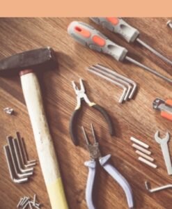 Hammer, screwdrivers, pliers, and other tools on a wooden tabletop