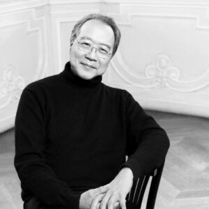 Black and white photo of a slightly smiling Chinese man in a black turtleneck and glasses