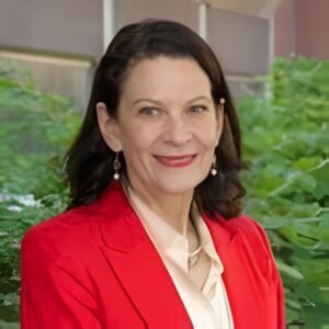 Smiling light skinned woman with brown hair wearing a red blazer
