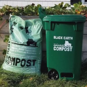 A bag of compost next to a green bucket with the words Black Forest Compost on it