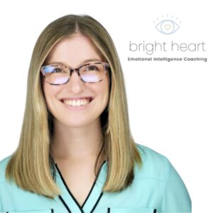 Smiling light skinned blonde woman with glasses in a turquoise shirt