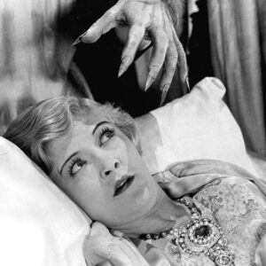 Human hand with extra sharp fingernails above a scared looking woman on a bed